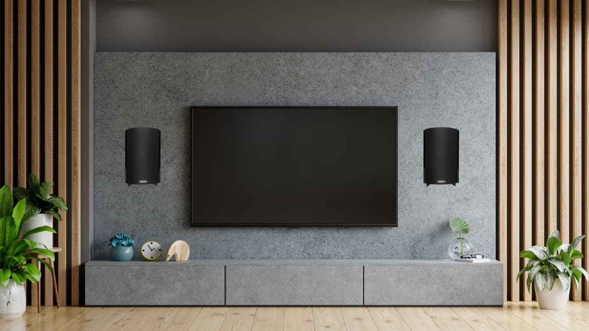 Modern living room setup with a wall-mounted TV and a home theater speaker system on each side.